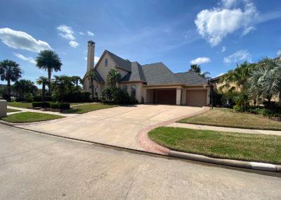 A large house with a driveway and palm trees.