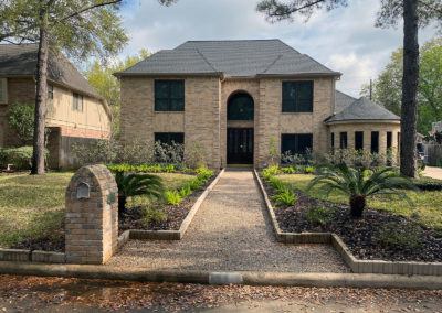 A large brick house with a garden in the front yard.